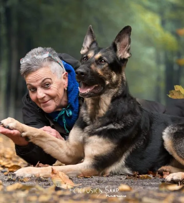 Mathilde Lehmann liegt mit ihrem Deutschen Schäferhund im Herbstlaub